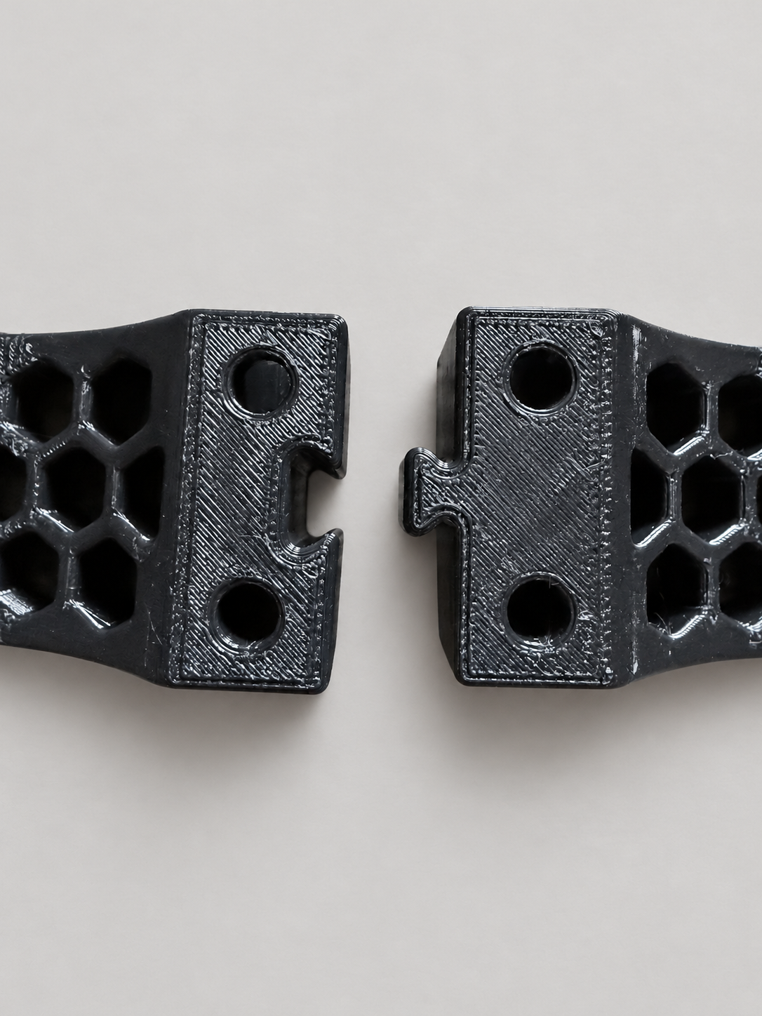 Close-up of the matching modular connectors on two black ABS tank cradle pieces, showing how additional sets can link together.